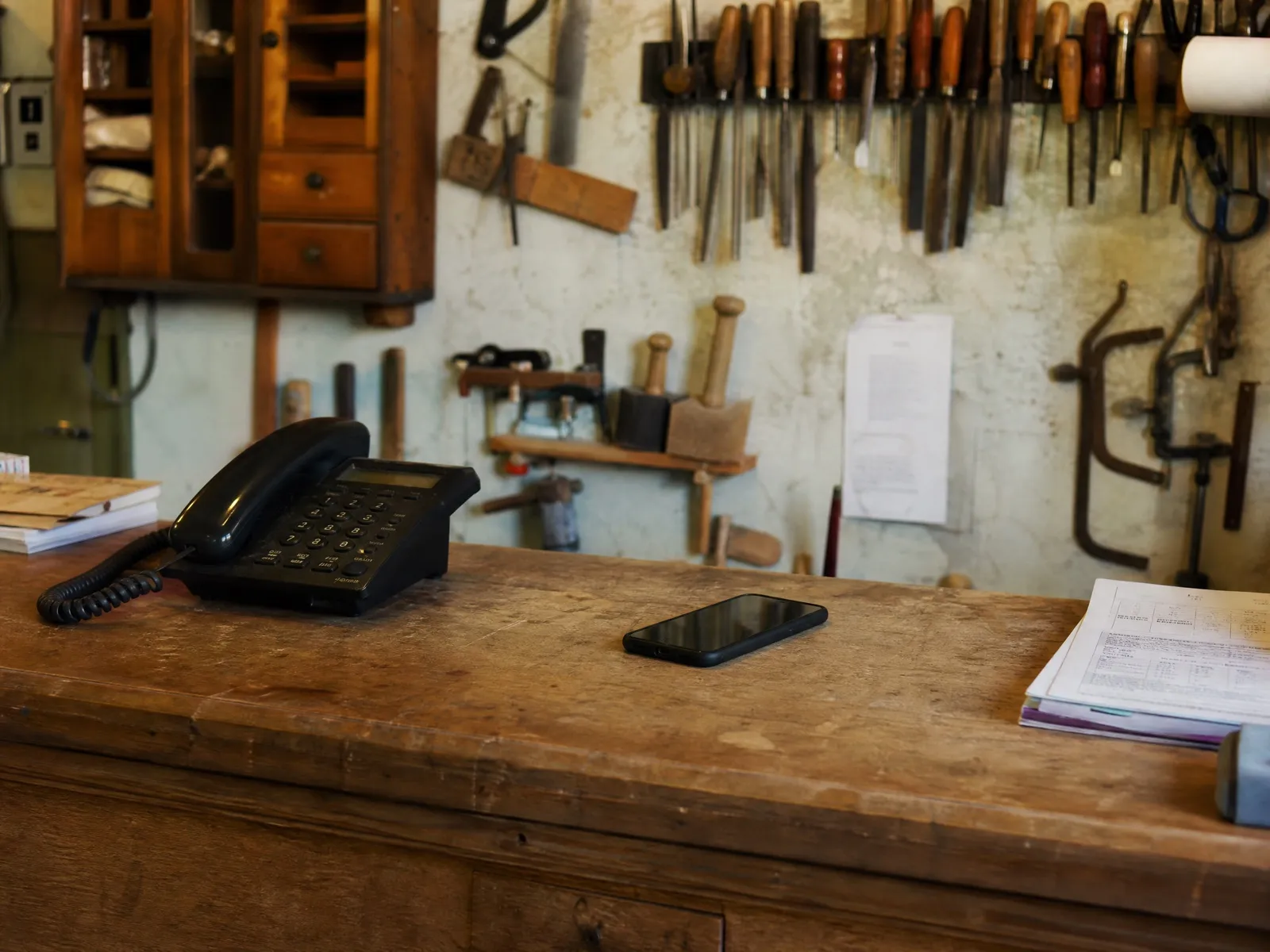 Téléphone portable retourné à côté d'un téléphone fixe sur le comptoir d'un atelier